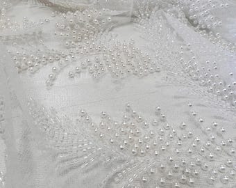 May include: White tulle fabric with pearl embellishments in a floral pattern.