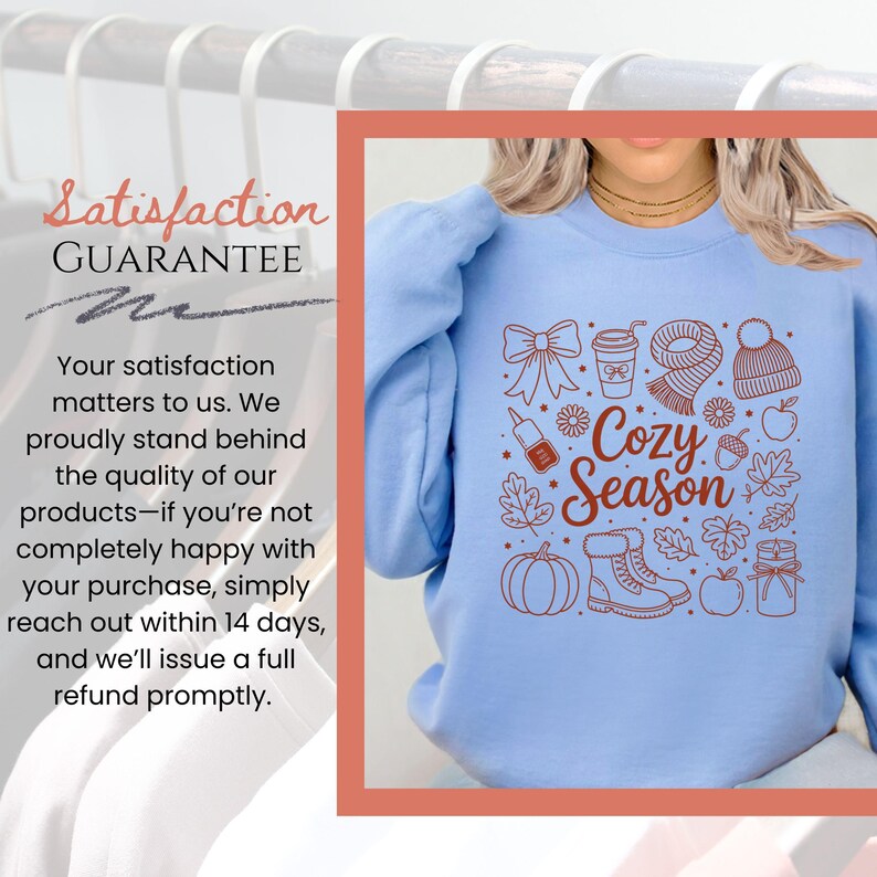 K&ouml;nnte beinhalten: Hellblaues Sweatshirt mit einem braunen Grafikdesign mit herbstlichen Elementen wie einem K&uuml;rbis, Bl&auml;ttern und einem Schal. Der Text "Cozy Season" ist ebenfalls enthalten. Das Bild enth&auml;lt auch den Text "Satisfaction Guarantee".