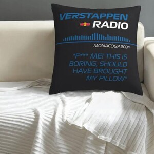 May include: Black square pillow with the text "VERSTAPPEN RADIO" in blue and white. Below the text is "MONACOGP 2024" and a quote that reads "F*** ME! THIS IS BORING, SHOULD HAVE BROUGHT MY PILLOW". The pillow is on a white couch.