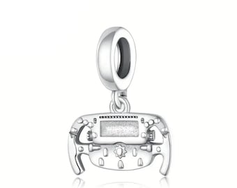 Pode incluir: Um pingente de prata em forma de volante, com um visor central e detalhes de botões. O pingente tem uma argola na parte superior para prender a uma pulseira ou colar. O design é muito detalhado e reflete a luz.