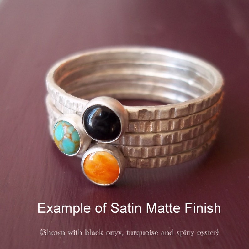 May include: Example of a satin matte finish on a silver ring with three gemstones. The gemstones are turquoise, black onyx, and spiny oyster.