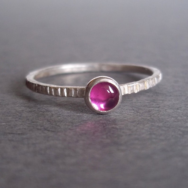 May include: A silver ring with a textured band and a pink gemstone.