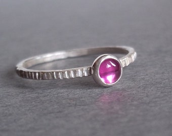 Puede incluir: Un anillo de plata con una banda texturizada y una piedra preciosa rosa.