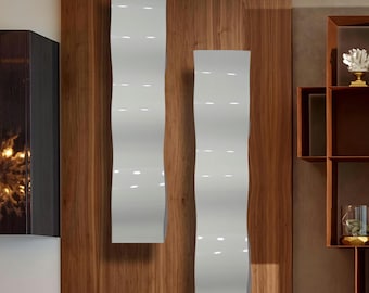 Puede incluir: Dos paneles de pared blancos, altos y ondulados, montados en una pared de madera. Los paneles tienen un acabado brillante y un diseño vertical ondulado. La madera tiene un patrón de vetas natural. Los paneles son un elemento de diseño moderno.