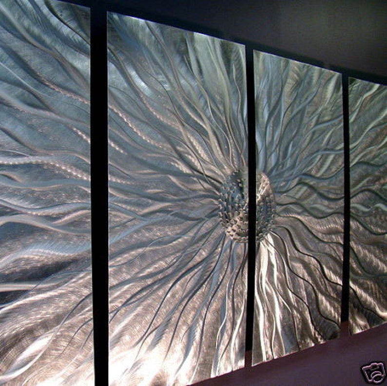May include: Abstract metal wall art, comprising four panels. The artwork features a central, textured sphere with radiating lines, all in a silver metallic finish. The panels are separated by black vertical lines. A modern, decorative piece.