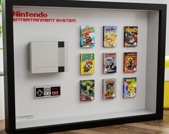 May include: A framed display featuring a Nintendo Entertainment System console, controller, and game cartridges. The frame is black, and the background is white. The text "Nintendo Entertainment System" is in red. The games include Super Mario Bros and Punch-Out!!