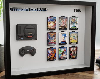 May include: A framed display featuring a black Sega Genesis console, controller, and nine game cartridges. The frame has the text "MEGA DRIVE" and "SEGA". A Sonic the Hedgehog figurine is in the foreground.