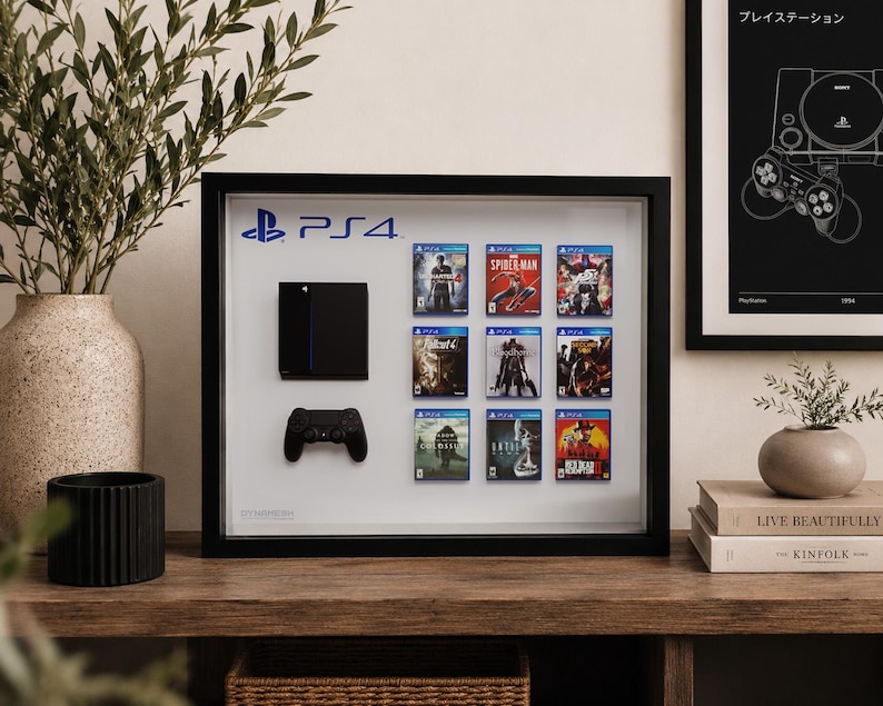 Peut inclure: Un cadre vitrine rectangulaire noir contenant une console noire montée, une manette de jeu noire et neuf boîtiers de jeux miniatures disposés en grille.