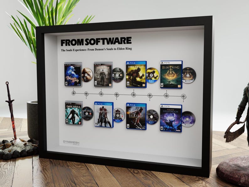 May include: Framed artwork featuring video game covers and discs from the "Souls" series, including "Dark Souls" and "Elden Ring." The black frame displays the games in chronological order, with the text "FROM SOFTWARE" at the top.