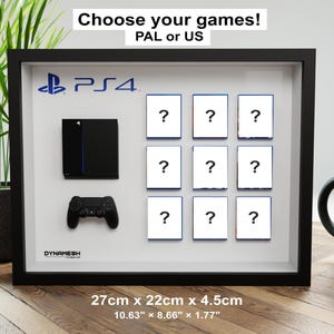 Peut inclure: Un cadre vitrine noir présentant une console noire miniature, une manette noire et neuf carrés blancs avec des points d'interrogation. Le cadre mesure 27cm par 22cm par 4,5cm. Le texte indique Choose your games! PAL or US.