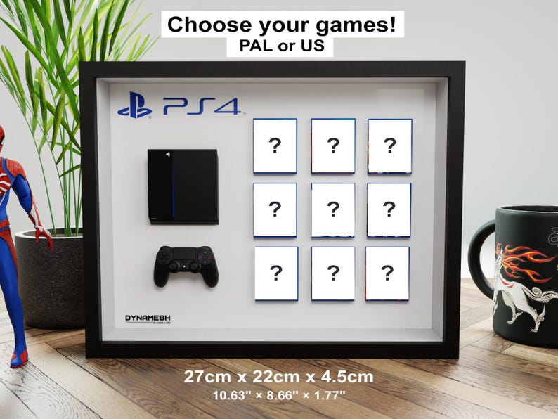 Peut inclure: Un cadre vitrine noir présentant une console noire miniature, une manette noire et neuf carrés blancs avec des points d'interrogation. Le cadre mesure 27cm par 22cm par 4,5cm. Le texte indique Choose your games! PAL or US.