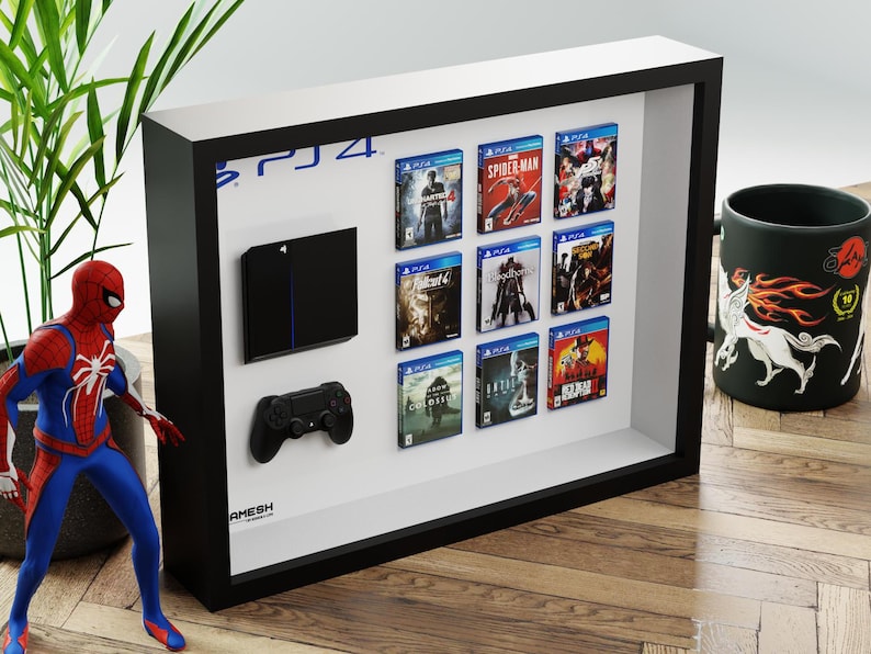 Peut inclure: Un cadre de présentation noir contenant une console de jeu miniature noire, une manette de jeu noire et neuf boîtiers de jeux miniatures disposés en grille.