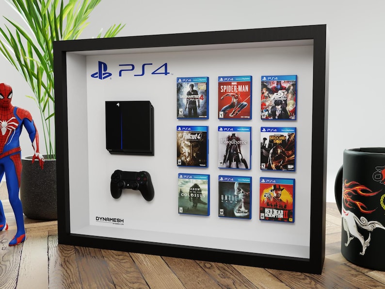 Peut inclure: Un cadre vitrine noir présentant une console, une manette de jeu noire et neuf boîtiers de jeux miniatures.