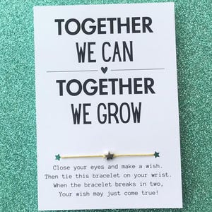 May include: A white card with the text "Together we can, Together we grow" and a yellow string bracelet with two silver stars. The card also includes instructions for making a wish with the bracelet.