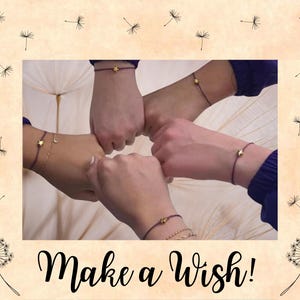 May include: Image features four wrists with matching bracelets, each with a small charm. The bracelets are dark red with gold charms, including stars and spheres. The phrase "Make a wish!" is written in black script at the bottom of the image.