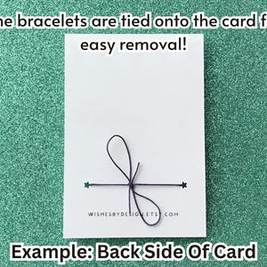 May include: A white card with a black string bow and two green star accents. Text on the card reads, "The bracelets are tied onto the card for easy removal!" and "Example: Back Side Of Card."