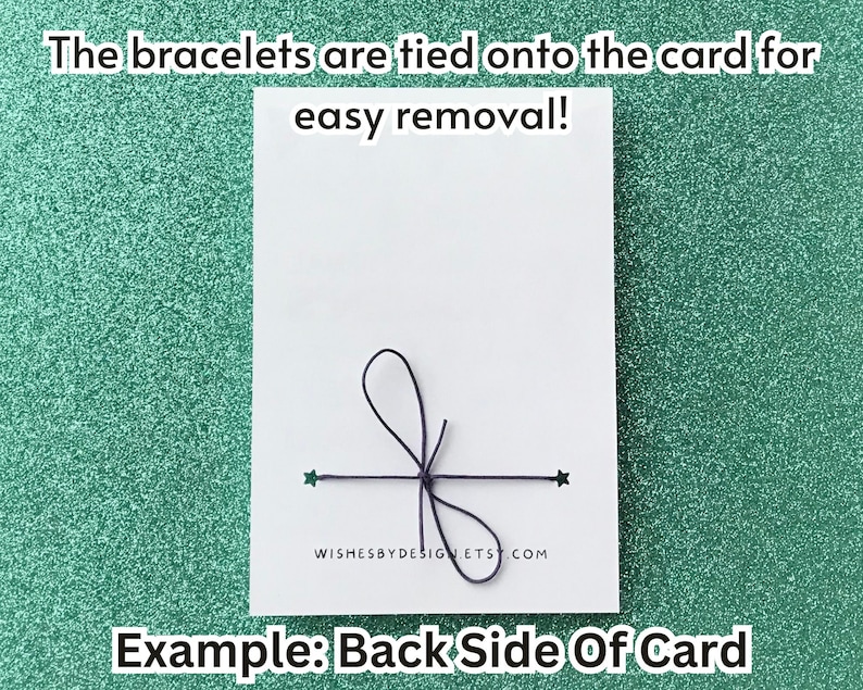 May include: A white card with a black string bow and two green star accents. Text on the card reads, "The bracelets are tied onto the card for easy removal!" and "Example: Back Side Of Card."