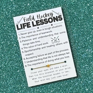 May include: A white card with the text "Field Hockey Life Lessons" and a list of life lessons. A gold star charm bracelet is attached. The card includes instructions to make a wish and tie the bracelet.