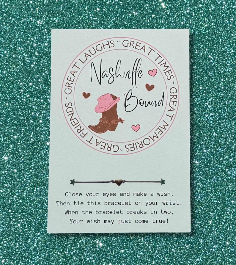 Peut inclure: Une carte blanche avec l'inscription "Nashville Bound" dans un motif circulaire avec une illustration de botte et de chapeau de cow-boy. La carte comprend les instructions pour un bracelet &agrave; souhait : "Fermez les yeux et faites un v&oelig;u."