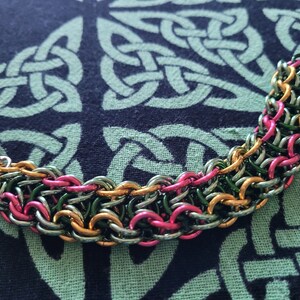 Peut inclure: Un bracelet en maille de chaîne multicolore avec des maillons roses, verts et dorés. Le bracelet est en métal et possède une fermeture à fermoir.