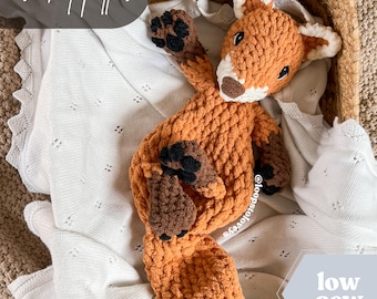 May include: A crocheted fox toy in orange and brown with a white blanket in the background. The text "crochet pattern" and "low sew" are visible in the image.