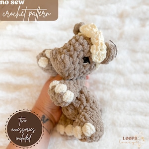 Könnte beinhalten: Ein gehäkeltes Plüschtier in Form eines Flusspferdes mit einer weißen Schleife. Das Flusspferd ist braun und hat weiße Akzente an seinen Füßen. Der Text "no sew crochet pattern" befindet sich oben im Bild. Der Text "two accessories included" befindet sich unten im Bild.