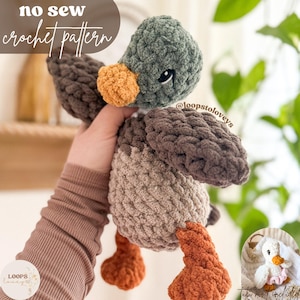 May include: A crocheted duck toy with a green head, brown body, and orange feet. The duck is being held by a hand. The text "no sew crochet pattern" is at the top of the image. The text "@loopstoloveys" is on the duck's wing. The text "Loops Loveys" is in the bottom left corner of the image.
