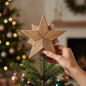 Può includere: Una stella decorativa in legno color marrone chiaro per la punta dell'albero, caratterizzata da un design geometrico a più strati con venature del legno visibili. La stella è posizionata sulla cima di un ramo di pino decorato con palline.