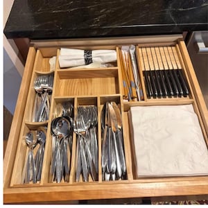 Könnte beinhalten: Ein hölzerner Schubladeneinsatz mit Besteck, darunter Gabeln, Löffel und Messer. Auch Essstäbchen und Servietten sind zu sehen. Das Besteck ist in separaten Fächern in der Schublade ordentlich angeordnet.