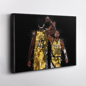 May include: Framed artwork featuring two basketball players in gold and navy uniforms, high-fiving. One player's jersey displays "Siakam 43," the other reads "Indiana 0." The background is black with white paint splatter effects.