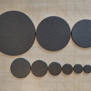 May include: A set of ten black round felt circles of varying sizes. The circles are arranged in a row, with the largest circle at the left and the smallest circle at the right.