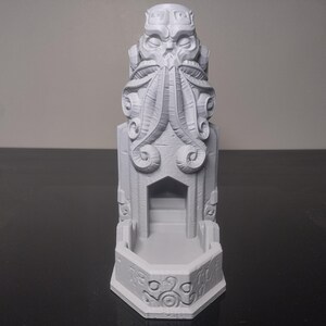 Puede incluir: Escultura gris impresa en 3D de una criatura estilizada con tentáculos y un diseño arquitectónico detallado. La escultura presenta una puerta central y tallas decorativas, con una altura aproximada de 15 cm.