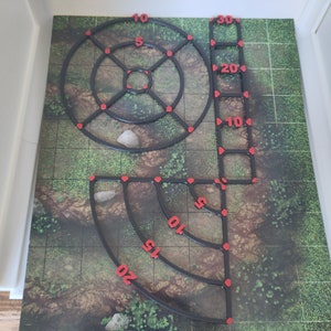 May include: A set of black plastic measuring tools for tabletop games. The tools include a ruler, a circle template, and a quarter circle template. The tools are marked with red numbers.