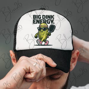 May include: A white and black trucker hat with a green pickle cartoon character holding a paddle and the text "BIG DINK ENERGY."