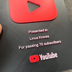 May include: A black and red YouTube Play Button award. The award is presented to Linus Knives for passing 70 subscribers. The YouTube logo is visible at the bottom of the award.