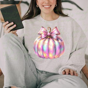 May include: A gray sweatshirt with a pink and iridescent pumpkin with a pink bow and a rhinestone in the center.