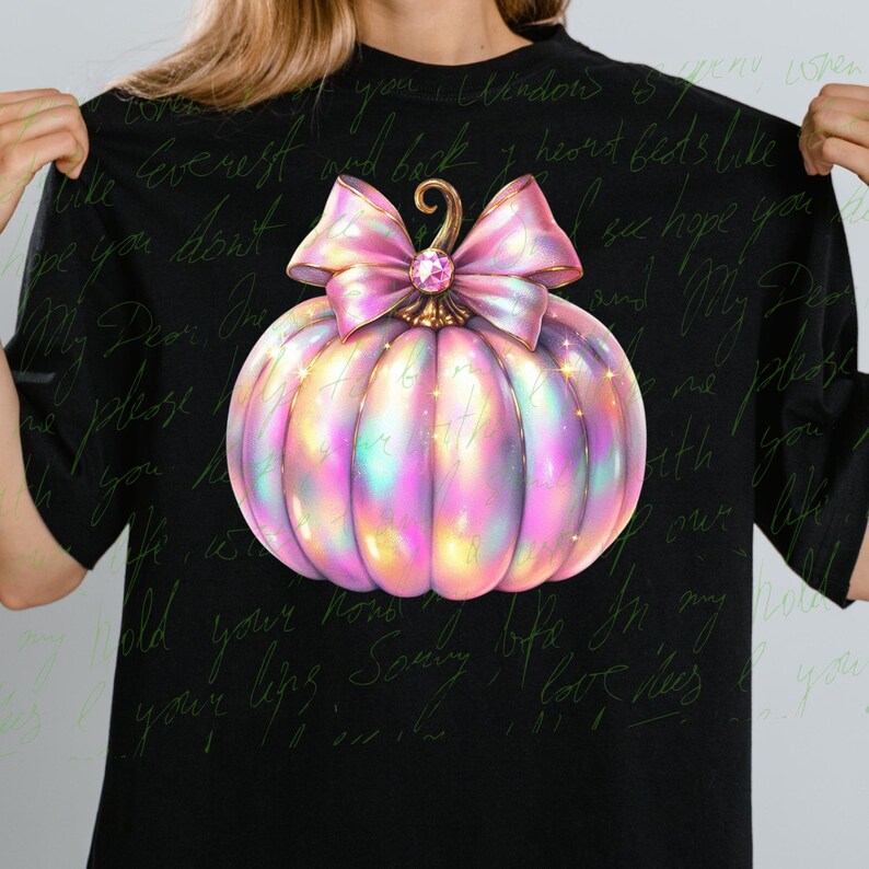 May include: A pink and iridescent pumpkin with a large pink bow and a rhinestone in the center. The pumpkin is on a black background with handwritten text.