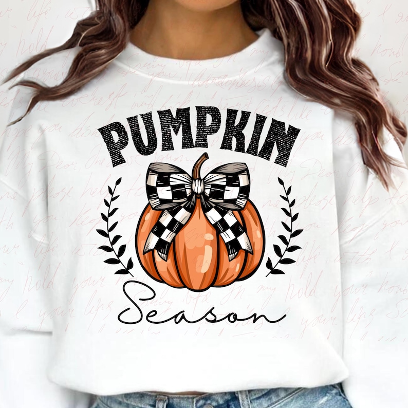 May include: White sweatshirt with a black and white checkered pumpkin with a bow and the text "Pumpkin Season" in black.