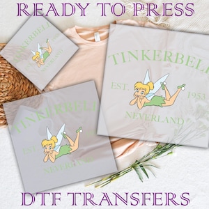 May include: Three iron-on transfers featuring Tinkerbell, the fairy from Peter Pan. Each transfer includes the text "Tinkerbell", "Est. 1953", and "Neverland".