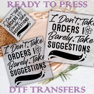 May include: Two iron-on transfers with the text "I Don't Take Orders I Barely Take Suggestions" in black with a flower and a swirl design. The transfers are ready to press.