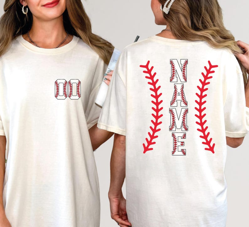 May include: Cream-colored t-shirt with baseball-themed design. The front features the number "00" in a baseball stitch design. The back displays the word "NAME" in a baseball font, flanked by red baseball stitching.
