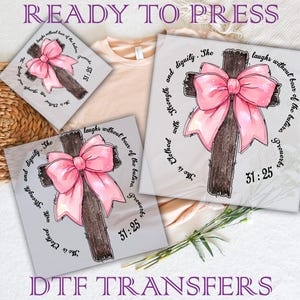 May include: DTF transfers displaying a cross with a pink bow and the Bible verse Proverbs 31:25. The text "READY TO PRESS" and "DTF TRANSFERS" are visible. The design is suitable for apparel and crafts.