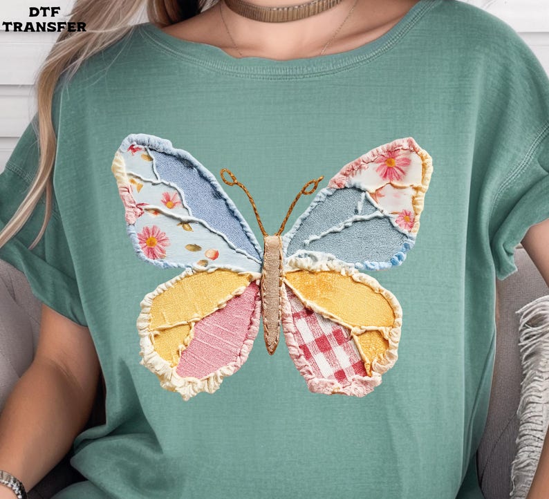 May include: A light green t-shirt featuring a colorful butterfly design. The butterfly has wings made of patchwork fabric in various patterns and colors, including floral, denim, and gingham. The text "DTF TRANSFER" is in the upper left corner.
