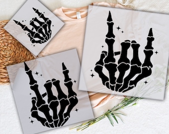May include: Three square sheets featuring black skeleton hand graphics making a rock and roll sign with small star accents. The text READY TO PRESS DTF TRANSFERS is printed in purple at the top and bottom of the image, surrounding the designs.