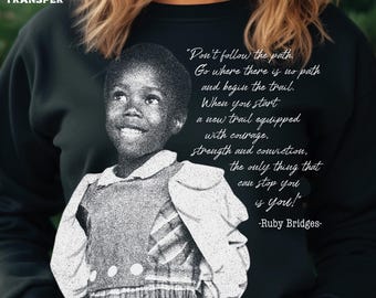 Pode incluir: Camisola preta com uma imagem a preto e branco de Ruby Bridges e uma citação. A citação diz: "Não siga o caminho. Vá para onde não há caminho e comece a trilha". As palavras "DTF TRANSFER" estão no canto superior esquerdo.