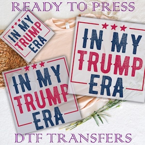 May include: White DTF transfers with the text "IN MY TRUMP ERA" in red and blue, with red stars. The phrase is inside a red border. The words "READY TO PRESS" and "DTF TRANSFERS" are also visible.