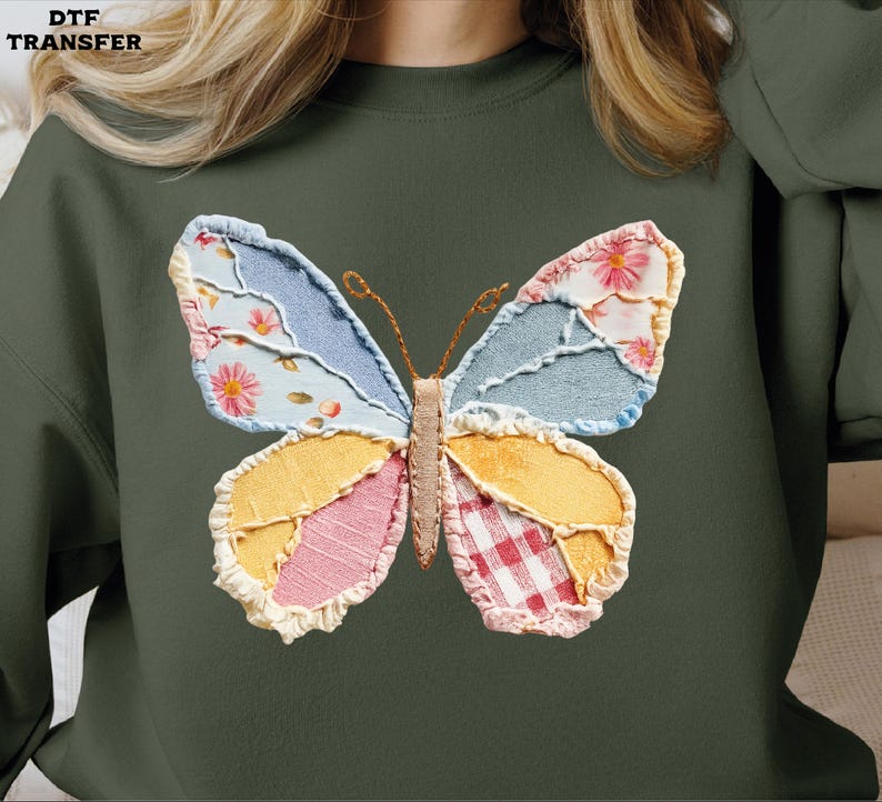 May include: Dark green sweatshirt featuring a colorful butterfly applique. The butterfly design incorporates various fabric patterns, including floral, denim, and gingham, in shades of blue, pink, yellow, and red. The text "DTF TRANSFER" is in the upper left corner.