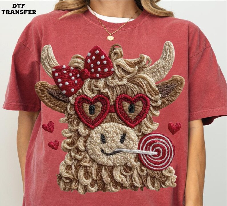 Pode incluir: Camiseta vermelha com um design bordado de uma vaca das Terras Altas com &oacute;culos de sol em forma de cora&ccedil;&atilde;o, um la&ccedil;o de bolinhas e um pirulito. A vaca tem um rosto sorridente e &eacute; cercada por cora&ccedil;&otilde;es bordados. O texto "DTF TRANSFER" est&aacute; no canto superior esquerdo.