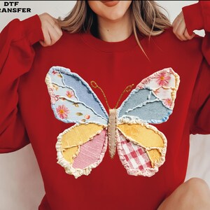 May include: A red sweatshirt featuring a large, colorful butterfly applique. The butterfly wings are patchwork, with floral, denim, and gingham patterns. The text "DTF TRANSFER" is in the upper left corner.