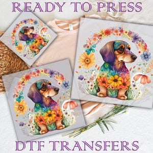 May include: DTF transfers featuring a watercolor dachshund dog adorned with colorful flowers and a floral wreath. The image includes the text "READY TO PRESS" and "DTF TRANSFERS". The design is suitable for apparel and craft projects.